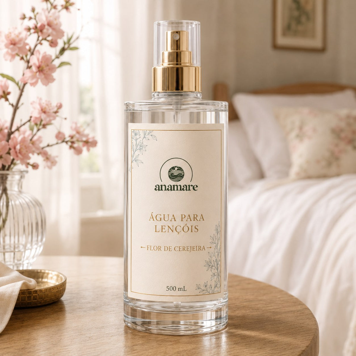 Água de Lençóis Anamare Flor de Cerejeira, frasco de vidro de 500 mL com válvula spray dourada e rótulo cru, em quarto com galho de cerejeira em flor