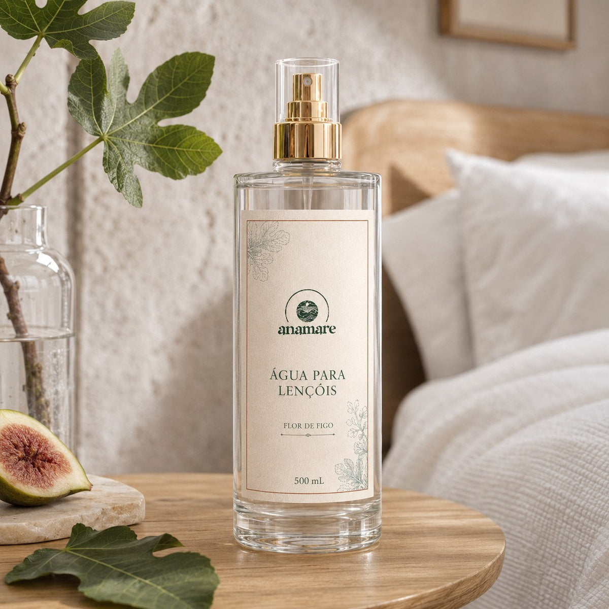 Água de Lençóis Anamare Flor de Figo, frasco de vidro de 500 mL com válvula spray dourada e rótulo cru, em parede de pedra com folha de figueira