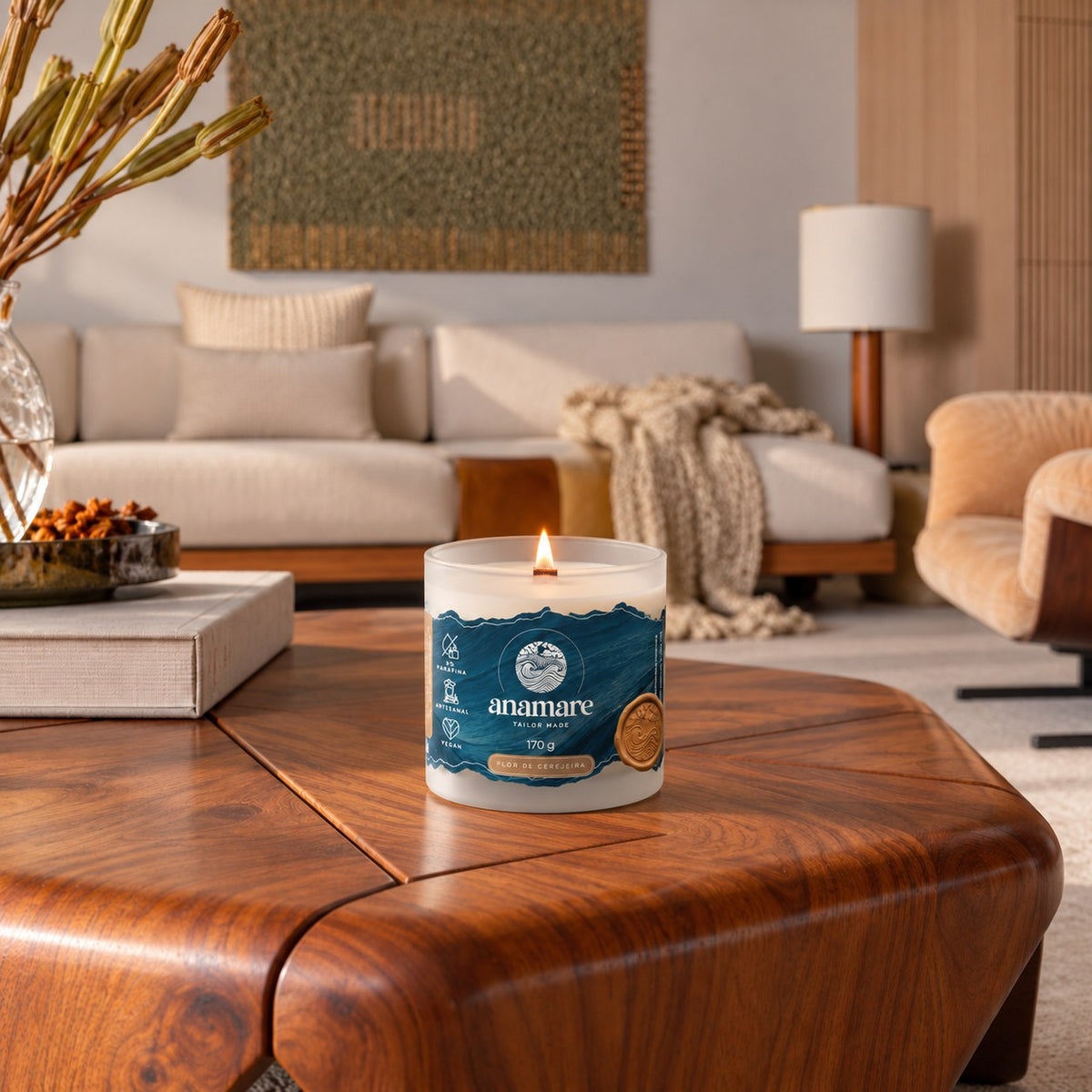 Vela aromática Anamare Grand 170 g Flor de Cerejeira acesa sobre mesa de madeira em sala de estar