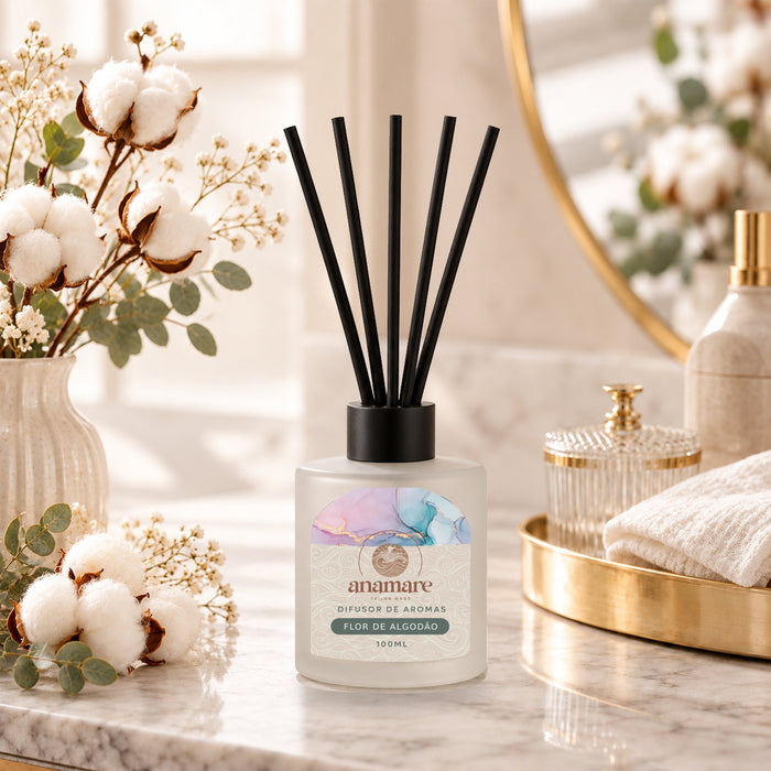 Difusor de Aromas Flor de Algodão 100 mL, frasco de vidro fosco com varetas pretas, em bancada de mármore com flores de algodão e eucalipto