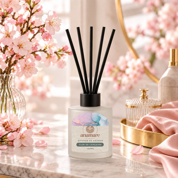 Difusor de Aromas Flor de Cerejeira 100 mL, frasco de vidro fosco com varetas pretas, em bancada de mármore com galhos de flor de cerejeira