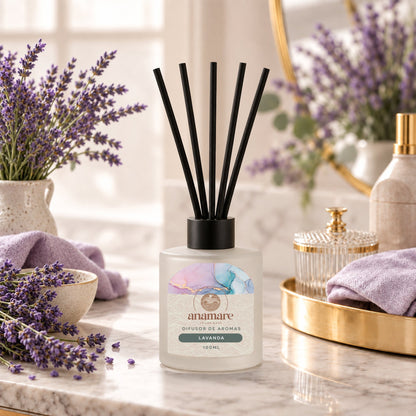 Difusor de Aromas Lavanda 100 mL, frasco de vidro fosco com varetas pretas, em bancada de mármore com ramos de lavanda e toalhas lilás