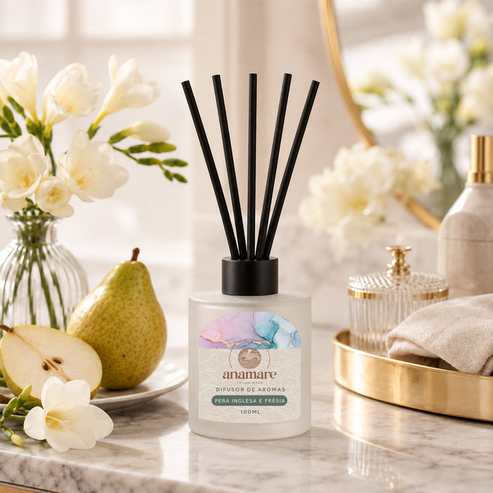 Difusor de Aromas Pera Inglesa e Frésia 100 mL, frasco de vidro fosco com varetas pretas, em bancada de mármore com peras e flores de frésia
