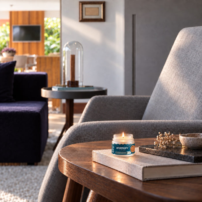 Sala com poltrona cinza e a vela Petit Flor de Algodão acesa sobre a mesa de madeira