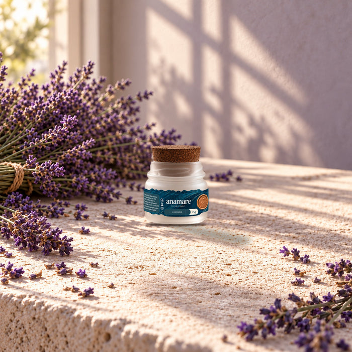 Vela aromática Petit 25 g Lavanda sobre bancada de pedra, entre ramos de lavanda