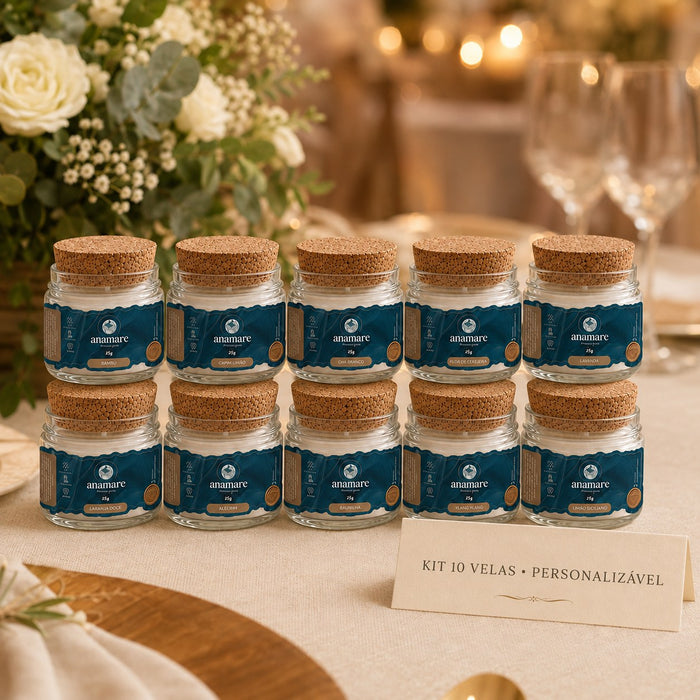 Kit de 10 lembrancinhas Anamare em detalhe: velas Petit de 25 g em potes de vidro com tampa de cortiça, cada rótulo com o nome da fragrância, sobre mesa posta de casamento com taças e rosas brancas