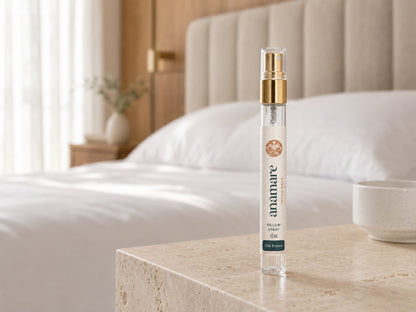 Pillow Spray Chá Branco 10 mL, flaconete de vidro com válvula spray dourada, em bancada de travertino, com tigela de porcelana ao lado e cama branca iluminada por luz filtrada