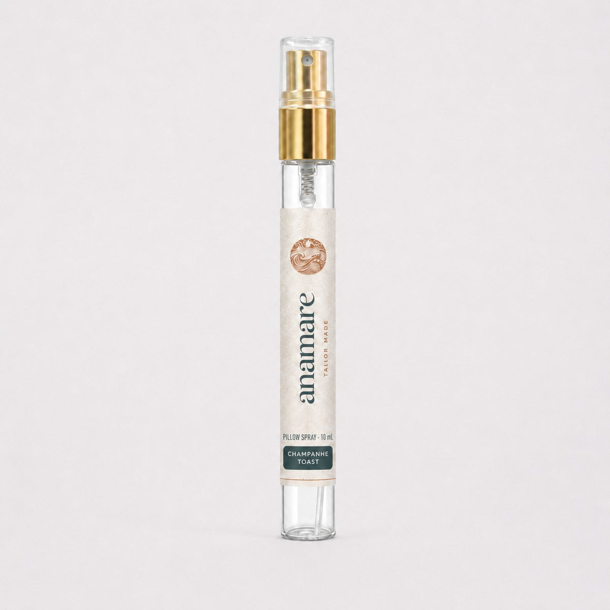 Pillow Spray Champanhe Toast 10 mL, flaconete de vidro com válvula spray dourada e rótulo Anamare, sobre fundo claro