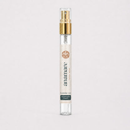 Pillow Spray Champanhe Toast 10 mL, flaconete de vidro com válvula spray dourada e rótulo Anamare, sobre fundo claro