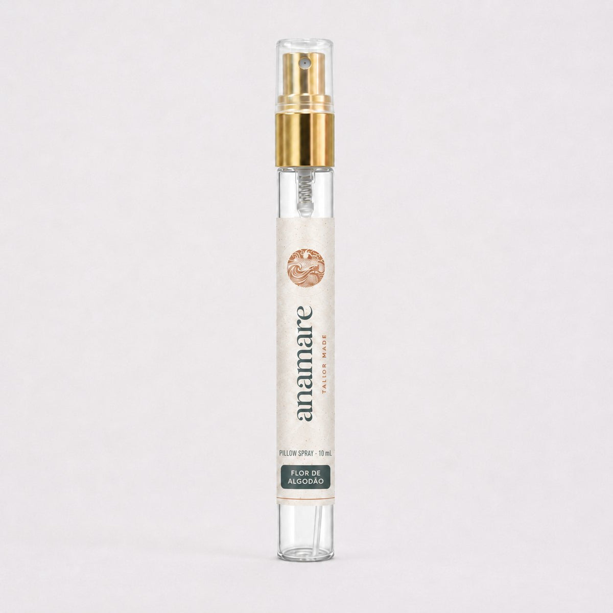 Pillow Spray Flor de Algodão 10 mL, flaconete de vidro com válvula spray dourada e rótulo Anamare, sobre fundo claro