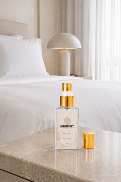 Pillow Spray Chá Branco 30 mL, frasco de vidro com válvula e tampa douradas, em quarto minimalista todo branco com luminária de pedra e cortina de voil, sobre bancada de mármore claro