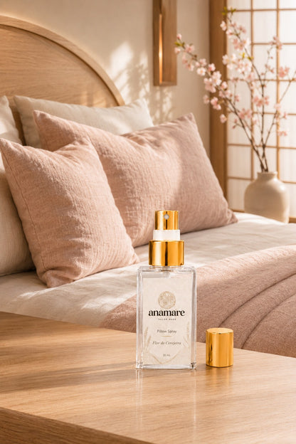 Pillow Spray Flor de Cerejeira 30 mL, frasco de vidro com válvula e tampa douradas, em quarto de inspiração japonesa com painel shoji, almofadas rosadas e galho de cerejeira em flor, sobre mesa de madeira clara