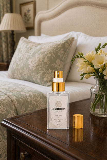 Pillow Spray Pera Inglesa e Frésia 30 mL, frasco de vidro com válvula e tampa douradas, em quarto clássico com cabeceira de linho, almofada de estampa floral verde e frésias amarelas em vaso de vidro, sobre criado-mudo de madeira escura