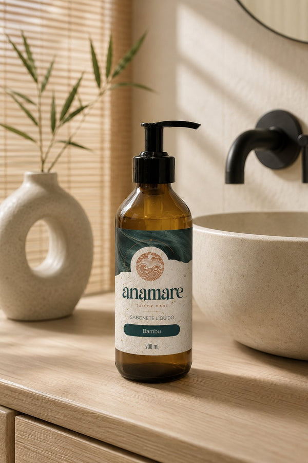 Sabonete Líquido para as Mãos Bambu 200 mL, frasco âmbar com válvula pump preta, em bancada de banheiro com cuba de pedra e a fragrância representada ao lado