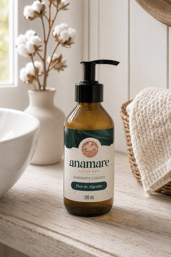 Sabonete Líquido para as Mãos Flor de Algodão 200 mL, frasco âmbar com válvula pump preta, em bancada de banheiro com cuba de pedra e a fragrância representada ao lado