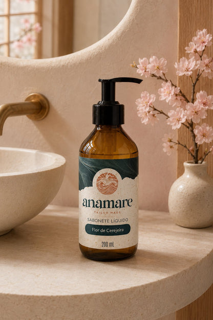 Sabonete Líquido para as Mãos Flor de Cerejeira 200 mL, frasco âmbar com válvula pump preta, em bancada de banheiro com cuba de pedra e a fragrância representada ao lado