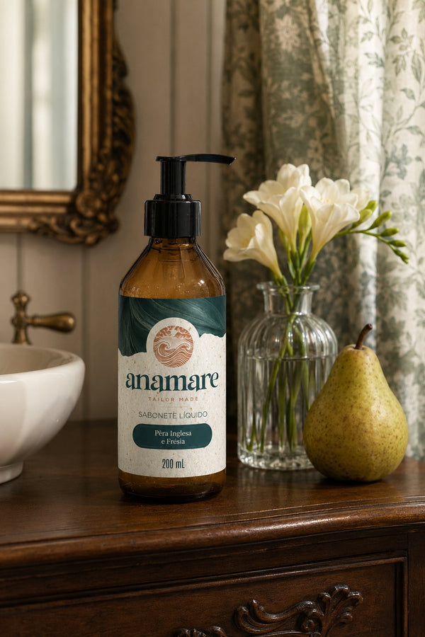 Sabonete Líquido para as Mãos Pera Inglesa e Frésia 200 mL, frasco âmbar com válvula pump preta, em bancada de banheiro com cuba de pedra e a fragrância representada ao lado