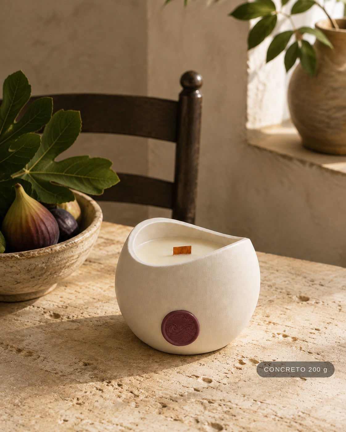 Vela Aromática Flor de Figo Concreto 200 g em mesa de travertino, ao lado de uma tigela de figos frescos. Selo de tamanho no canto: CONCRETO 200 g