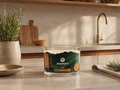 Vela Aromática Alecrim Signature 500 g com três pavios de madeira, pote de vidro grosso em bancada de cozinha com vaso de alecrim e tabua de madeira
