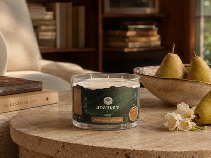 Vela Aromática Pera Inglesa e Frésia Signature 500 g com três pavios de madeira, pote de vidro grosso em mesa de biblioteca com peras e fresias brancas