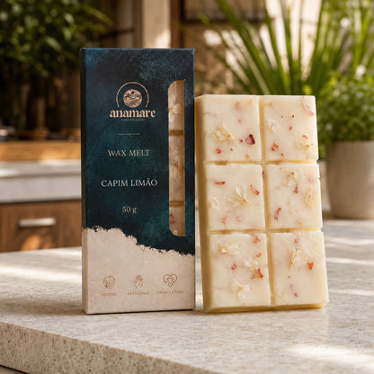 Wax Melt Anamare Capim Limão de 50 g, barra de cera vegetal com pétalas secas ao lado da caixa azul-petróleo com janela, em varanda gourmet em luz da manhã, com folhagem verde e bancada de granilite claro